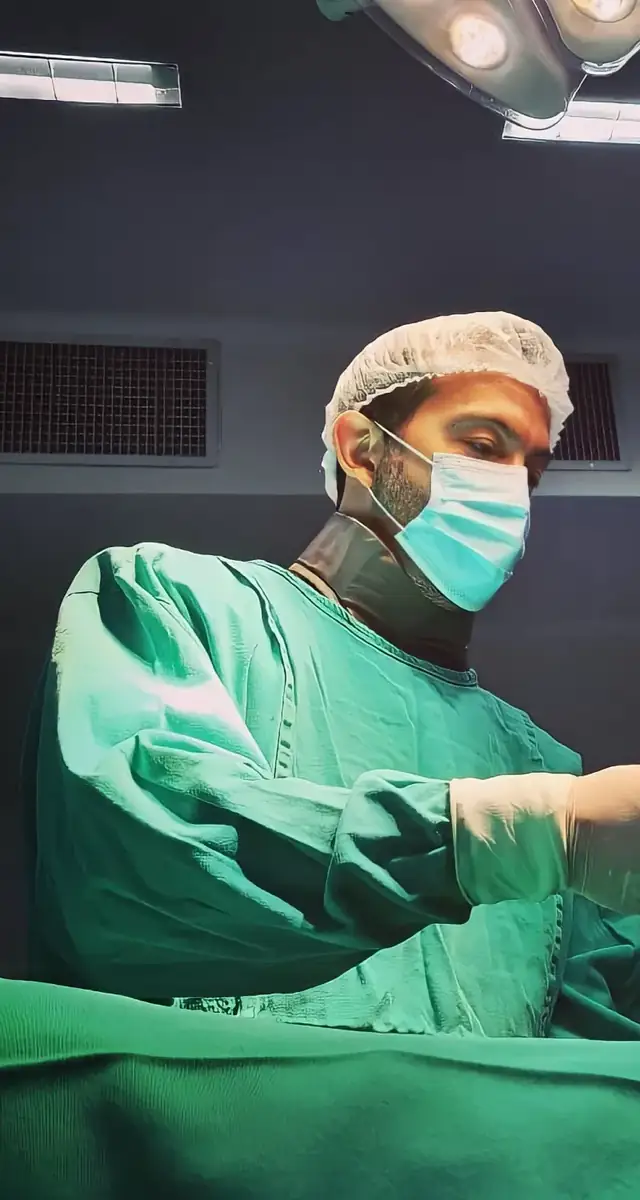 Dr. Luciano Morais de touca, máscara e roupa verde no centro cirúrgico
