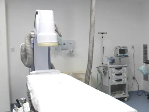 Sala de procedimentos vazia, com a mesa e o arco de angiografia
